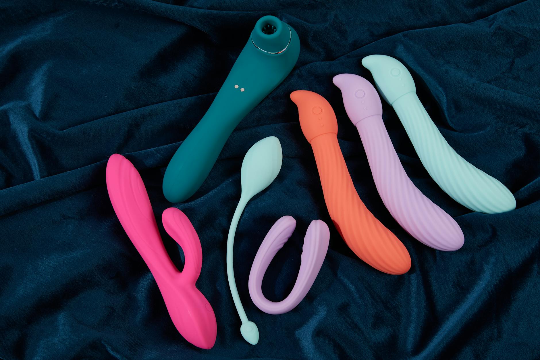 Woman holding a blue and pink silicone vibrator in a contemplative pose