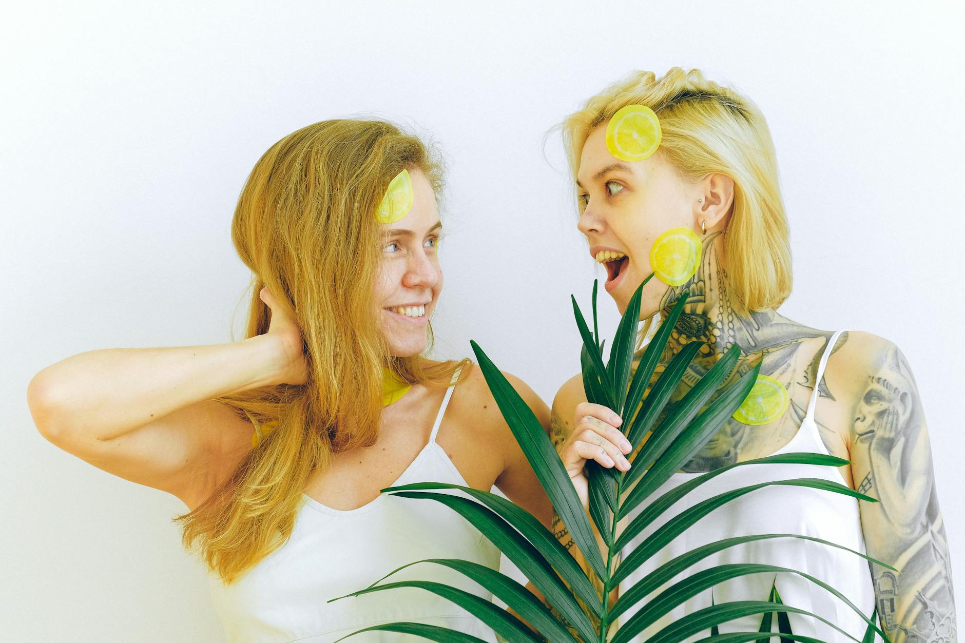 Two women smiling indoors with plants, expressing contentment and ease together.