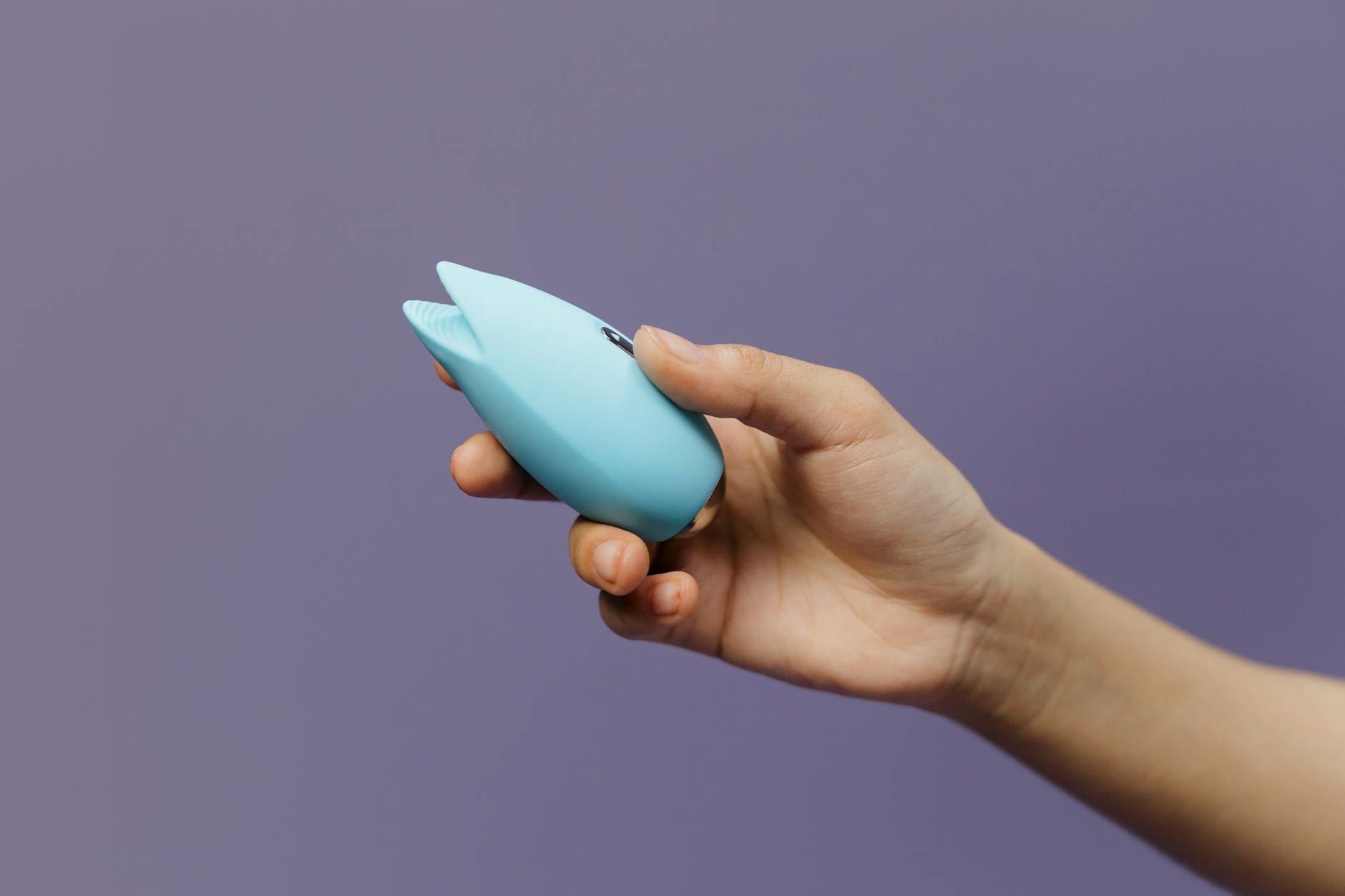 A young couple standing together indoors, holding a blue vibrator, symbolizing modern intimacy and shared exploration.